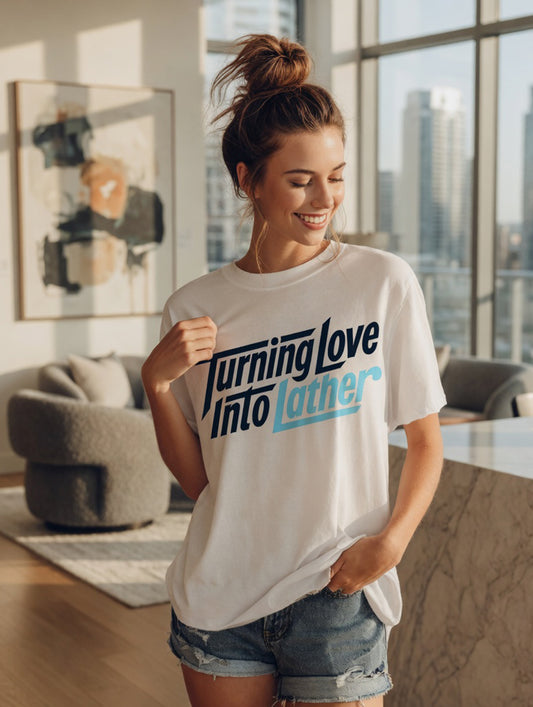 Brunette woman, in modern apartment, city scape in background, Solid White Blend t-shirt with modern 'Turning Love Into Lather' blue and navy graphic